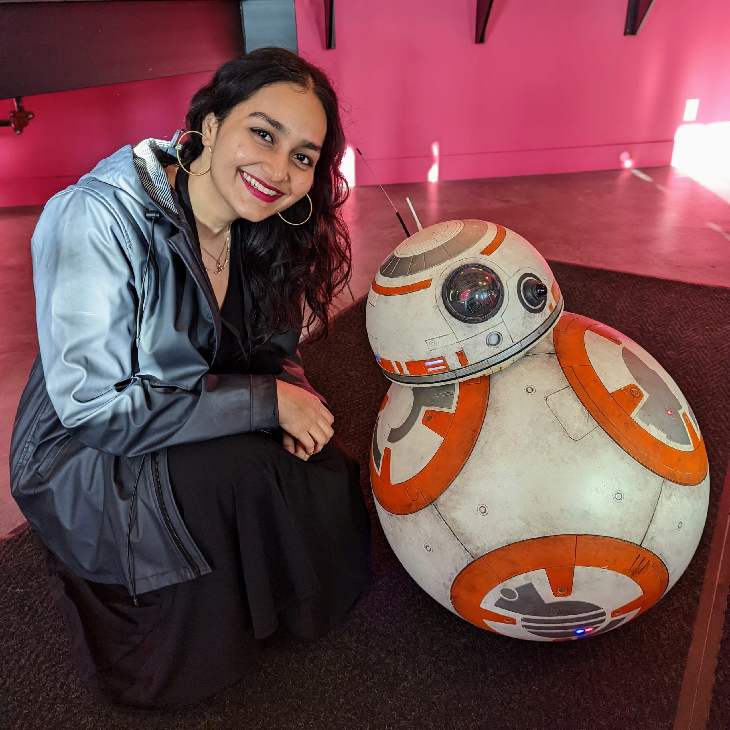 Asna crouching next to a replica of BB-8 from Star Wars